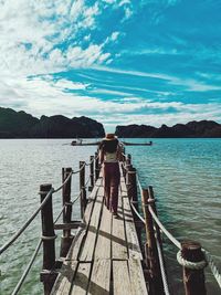 Rear view of man standing on pier over lake