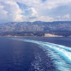 Scenic view of sea by mountains against sky