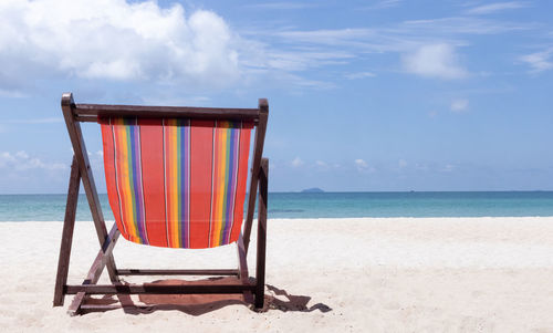 Deck chairs on beach against sky