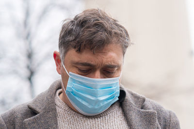 Headshot of a man covering his face with a medical mask to protect his nose and mouth