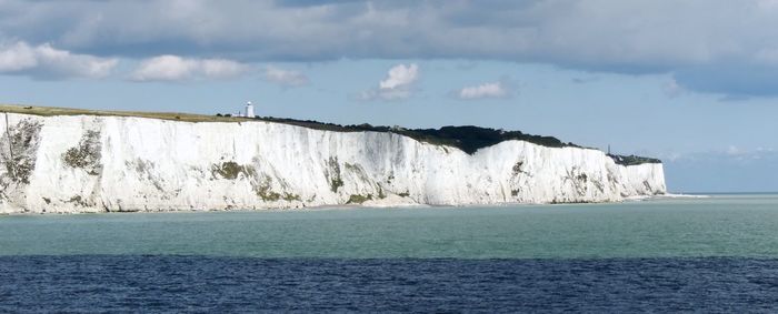 Scenic view of sea by leaf against cloudy sky