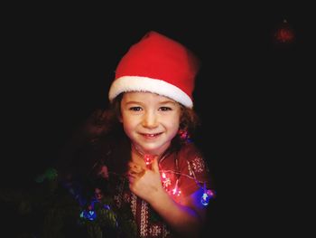 Portrait of cute girl wearing santa hat in darkroom