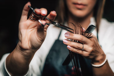 Midsection of woman cutting hairs in hair salon