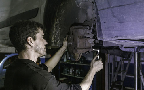 Side view of young man repairing car