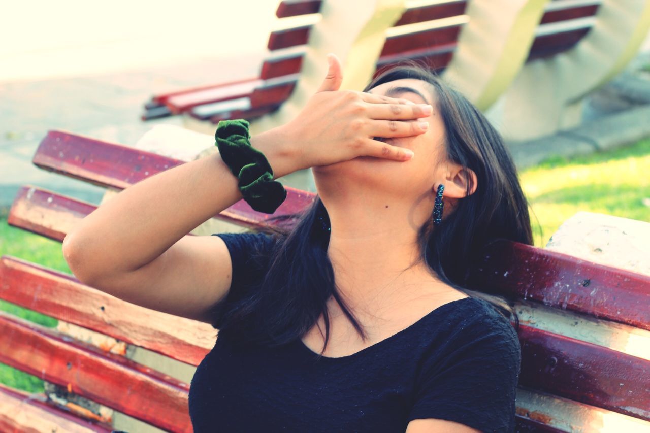 one person, real people, young women, casual clothing, leisure activity, lifestyles, young adult, bench, women, focus on foreground, front view, day, hairstyle, hair, seat, portrait, relaxation, sitting, adult, outdoors, beautiful woman