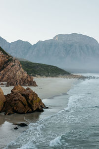 Scenic view of sea and mountains against clear sky.