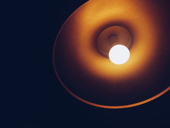 Low angle view of illuminated light bulb against black background