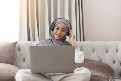 Portrait of young woman using laptop at home