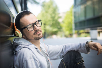 Side view of mature man listening music while sitting on road