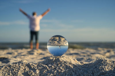 Person standing on rock at beach against sky