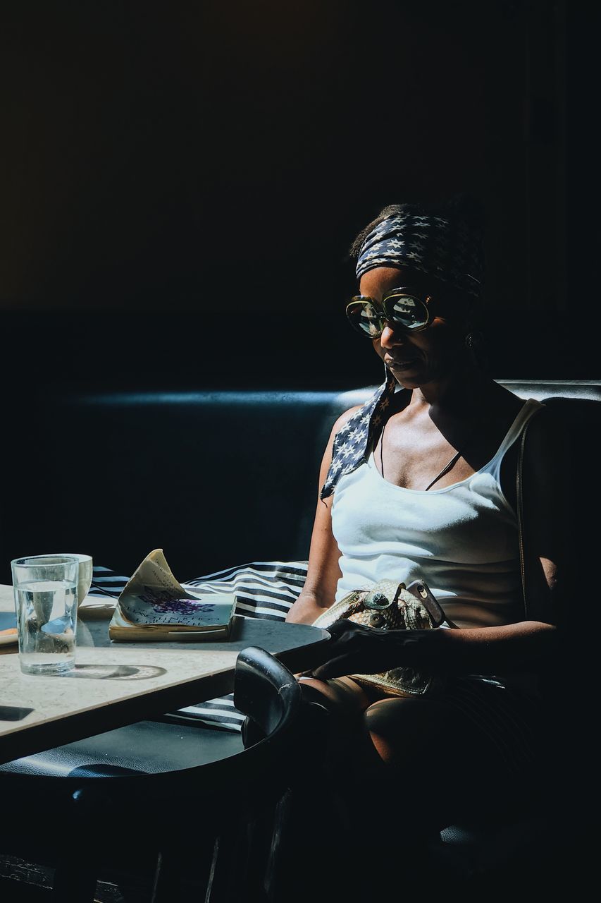 one person, table, sitting, glasses, real people, young adult, three quarter length, indoors, young men, front view, looking away, publication, casual clothing, looking, fashion, leisure activity, lifestyles, book, eyeglasses, contemplation