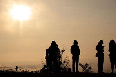 Silhouette people standing against sky during sunset