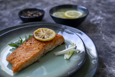 Side viewof salmon fish fillet cooked with different spices and served on plate.