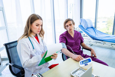 High angle view of doctor checking blood pressure of patient at hospital