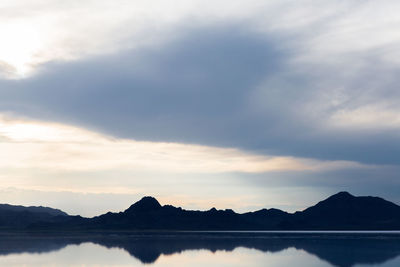 Scenic view of lake by silhouette mountains against sky