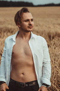 Young man looking away while standing on land