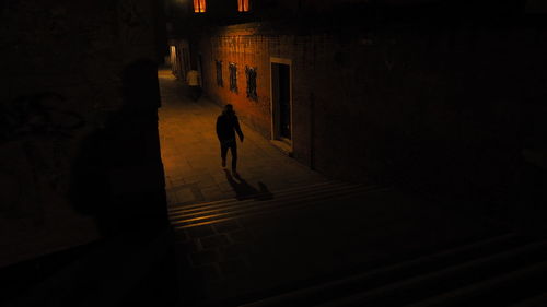 Silhouette person walking on street at night