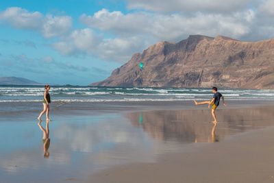 People playing on beach against sky