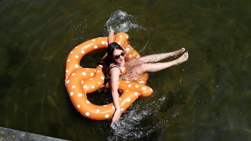 High angle view of woman sitting in inflatable ring on lake