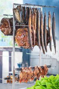 Various dry smoked spiced fish with smoke on background ready to eat in a fish market, vertical