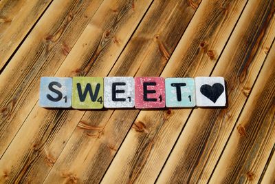 High angle view of text and heart shape made with toy blocks on wooden table