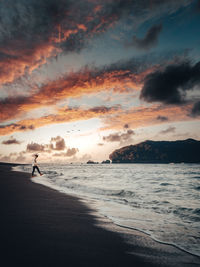 Silhouette person on beach against sky during sunset