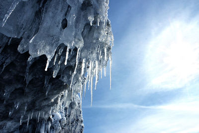 Low angle view of icicles on rock against sky