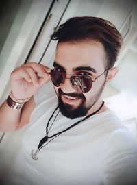 Portrait of smiling young man wearing sunglasses at home