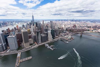 Aerial view of city by river and buildings against sky