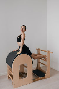 Full length of young woman exercising in gym