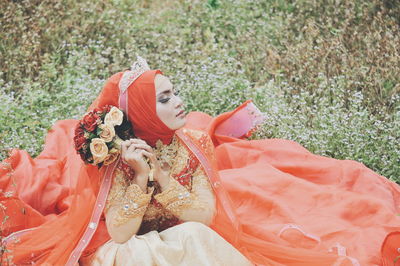 Bride wearing wedding dress while sitting on grassy field at park