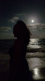 Woman standing on beach at night