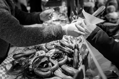 Midsection of woman giving pretzel to customer at market