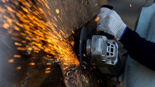 Industrial worker using angel grinder cutting metal, angel grinder cutting metal with bright sparks,