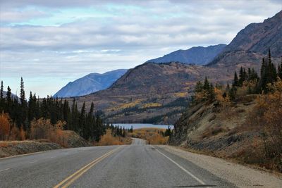 Empty road along landscape and mountains against sky