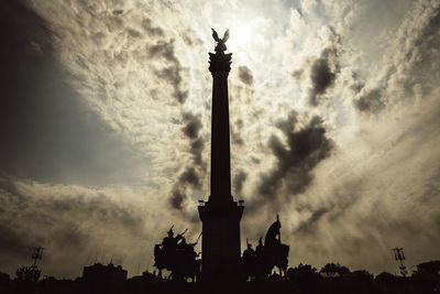 Low angle view of silhouette monument against cloudy sky
