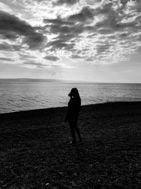 Silhouette woman photographing sea against sky