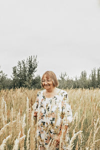 Portrait of woman standing on field against sky