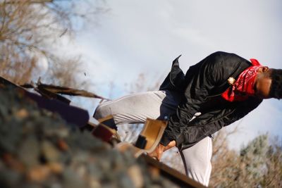 Tilt shot of man on railroad tracks against sky