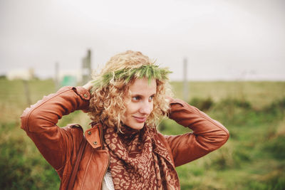 Portrait of young woman standing on field against sky