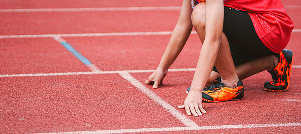 Low section of woman running with red umbrella