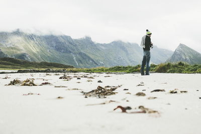 Rear view of man standing on mountain against sky