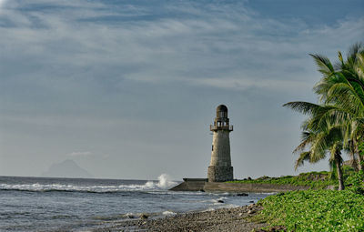 Lighthouse by sea against sky