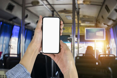 Midsection of man using mobile phone in bus