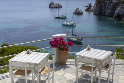 Restaurant tables by the sea outdoor terrace with a few yachts in the background in skopelos, greece