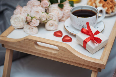 Romantic breakfast with coffee, waffles, gift box and rose flowers.