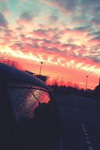 Silhouette car against dramatic sky during sunset