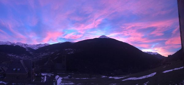 Scenic view of mountains against cloudy sky at sunset