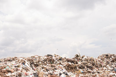 Heap of garbage against cloudy sky at recycling center