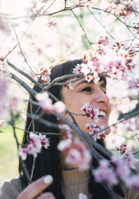 Low angle view of woman and pink flowering tree